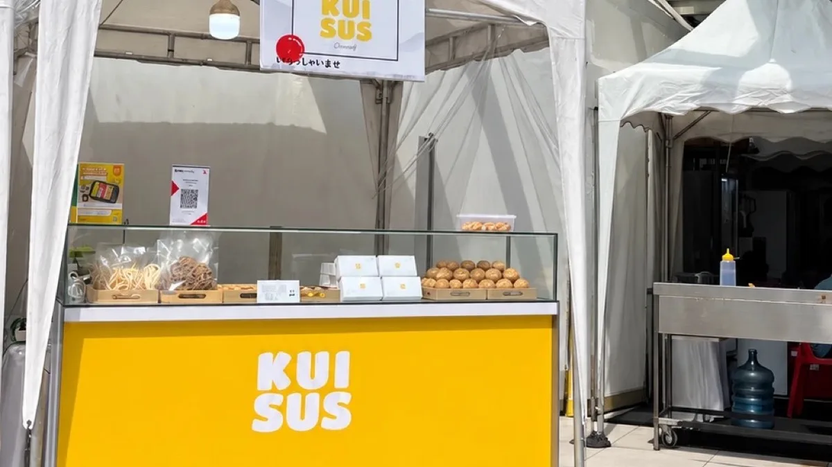 Stan bazaar KUISUS dengan etalase kaca dan meja kuning