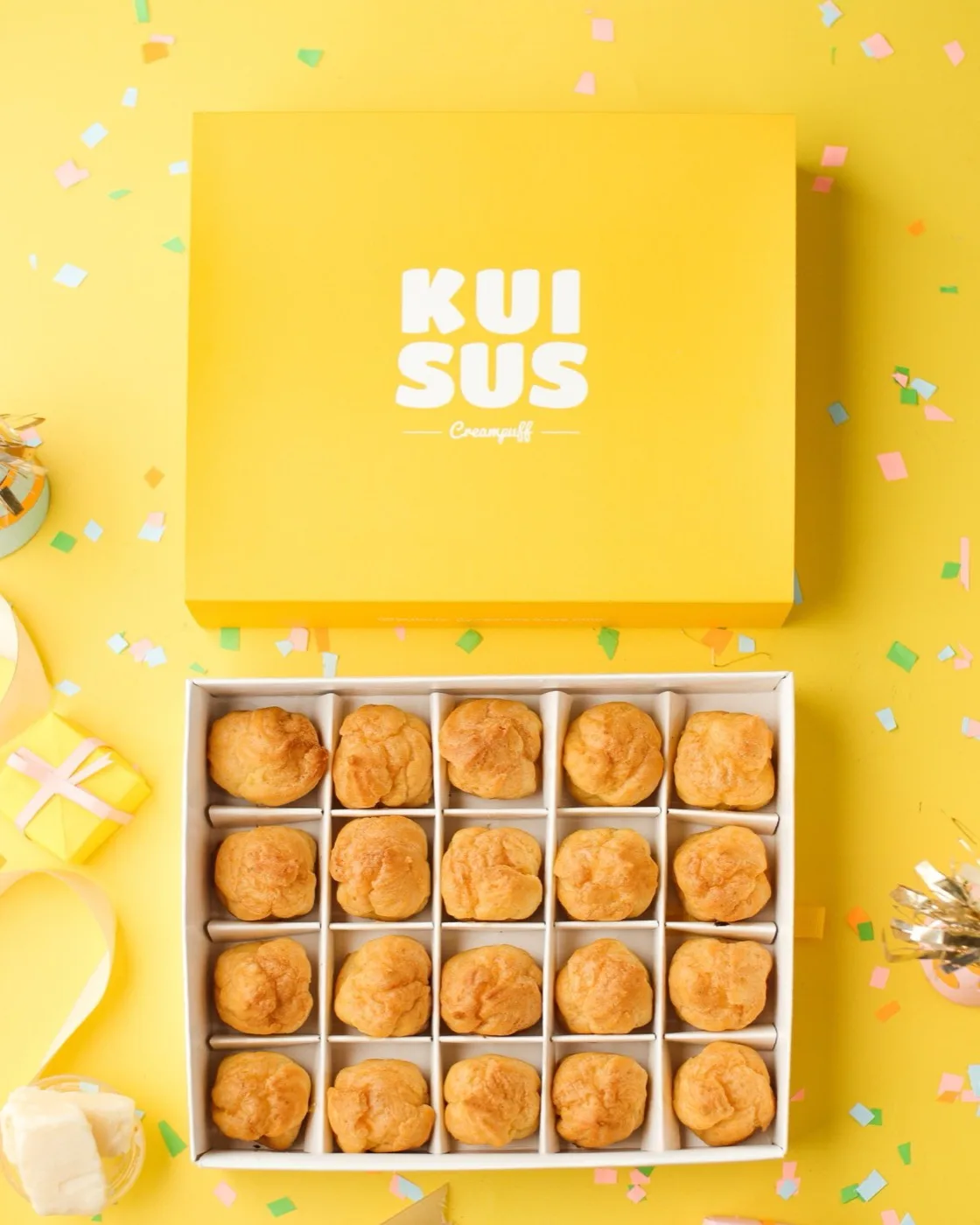 Gift box kuning KUISUS isi 20 kue sus di atas meja pesta